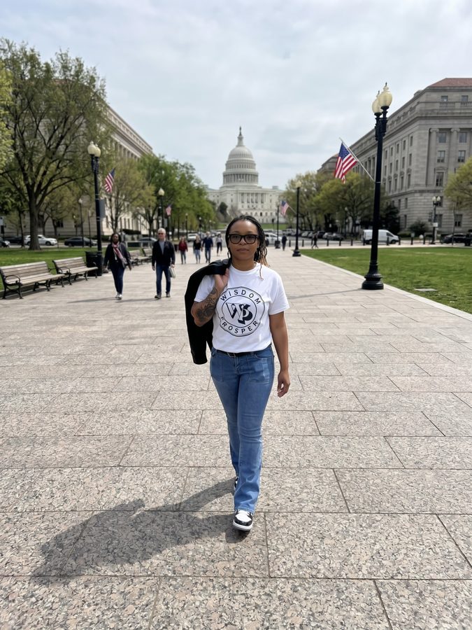Erica walking in Washington, D.C., wearing a Wisdom Prosper t-shirt with the U.S. Capitol behind her